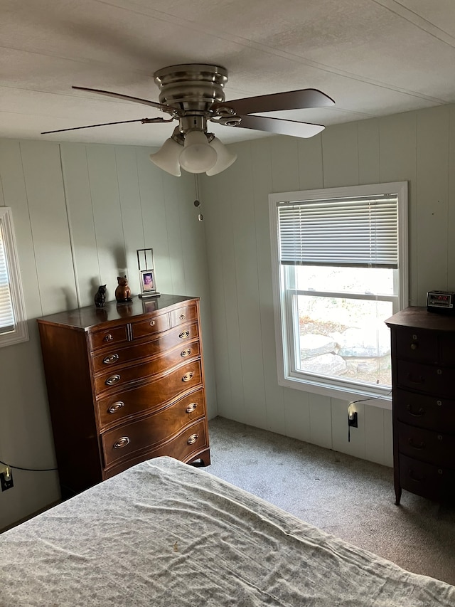 unfurnished bedroom with wood walls, carpet flooring, and ceiling fan