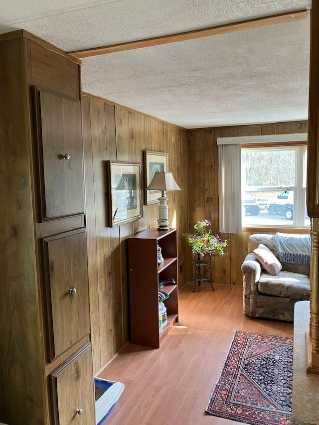 office area with wooden walls, a textured ceiling, and light hardwood / wood-style floors