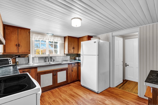 kitchen featuring white refrigerator, stove, sink, tasteful backsplash, and light wood-type flooring