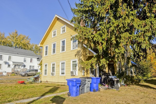 rear view of house with cooling unit and a yard