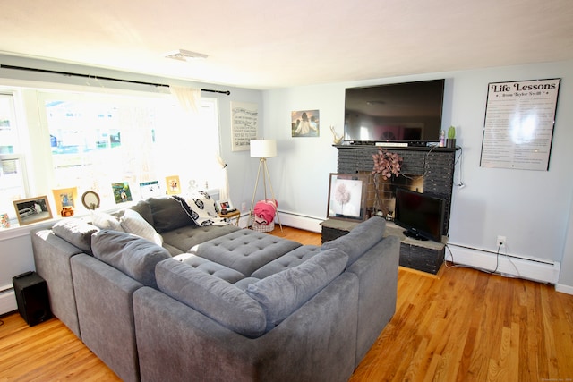 living room featuring light hardwood / wood-style floors, a fireplace, and a baseboard radiator