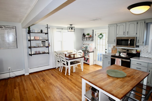 kitchen featuring gray cabinetry, stainless steel appliances, a barn door, backsplash, and light wood-type flooring