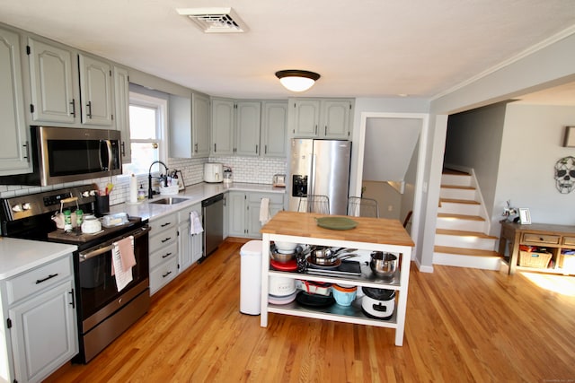 kitchen with decorative backsplash, stainless steel appliances, light hardwood / wood-style floors, and sink