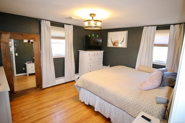 bedroom with light hardwood / wood-style floors, multiple windows, and a notable chandelier