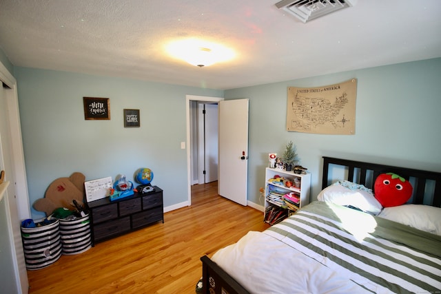 bedroom featuring a textured ceiling and light hardwood / wood-style flooring