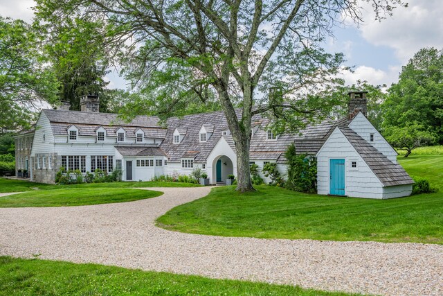 view of front of house with a chimney, a front lawn, and gravel driveway