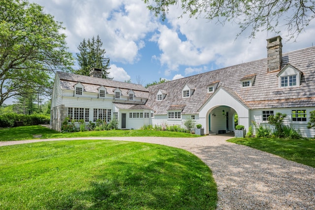 view of front of house featuring a chimney, a front lawn, and driveway