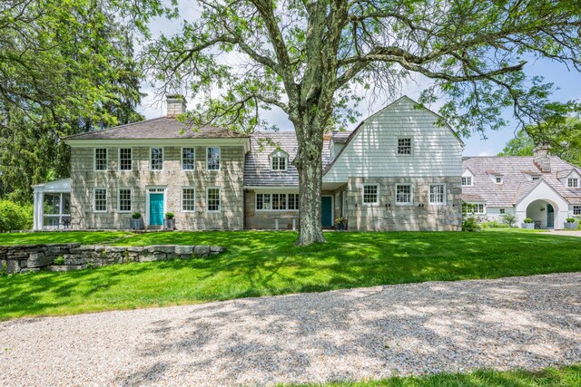 view of front of home with stone siding, a front yard, and a chimney