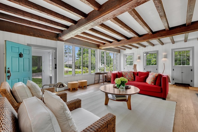 living room with light wood-style floors, beam ceiling, and wood walls