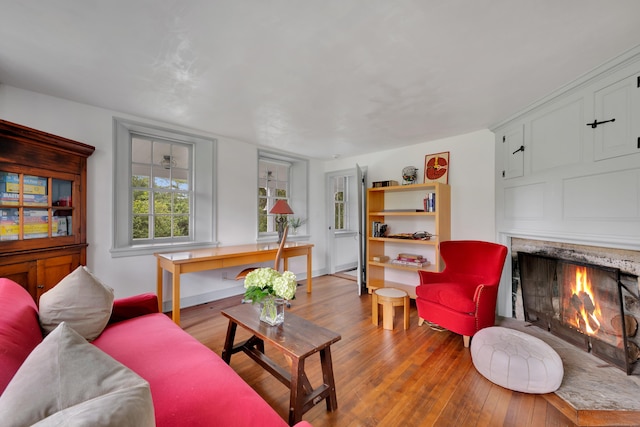 living area with hardwood / wood-style flooring and a warm lit fireplace