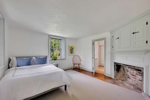 bedroom featuring light wood-style floors and a fireplace with flush hearth