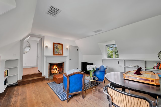 sitting room featuring hardwood / wood-style floors, a fireplace, vaulted ceiling, and stairs