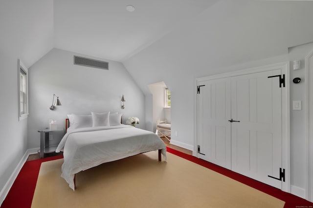 bedroom with vaulted ceiling, wood finished floors, and a closet