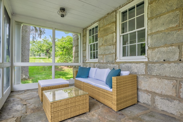 sunroom with stone finish floors, an outdoor living space, and wood ceiling