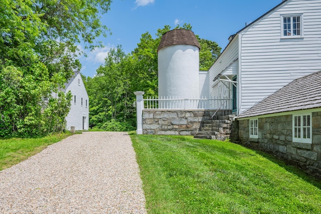 view of green lawn with gravel driveway