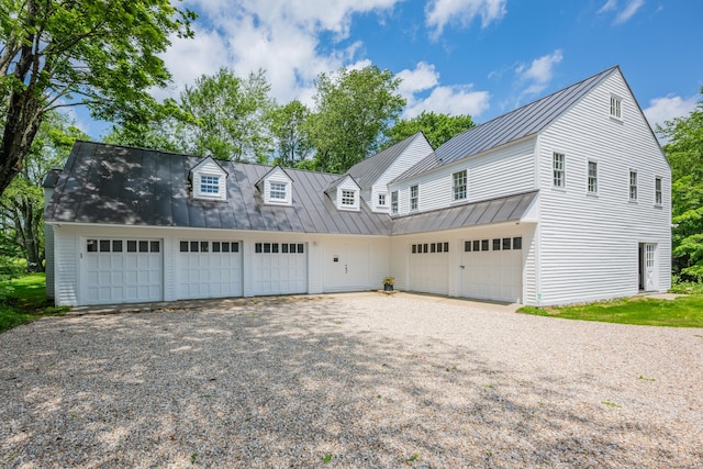 view of front of house featuring a standing seam roof, driveway, an attached garage, and a metal roof