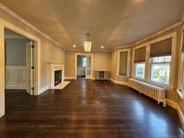 unfurnished living room with dark wood-type flooring, radiator heating unit, a notable chandelier, and ornamental molding