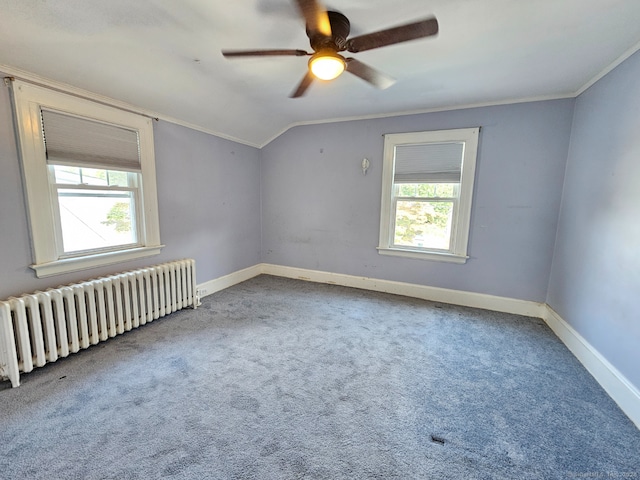 empty room with vaulted ceiling, radiator, carpet floors, ornamental molding, and ceiling fan