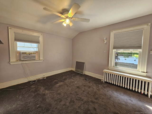 empty room featuring cooling unit, lofted ceiling, radiator, dark carpet, and ceiling fan