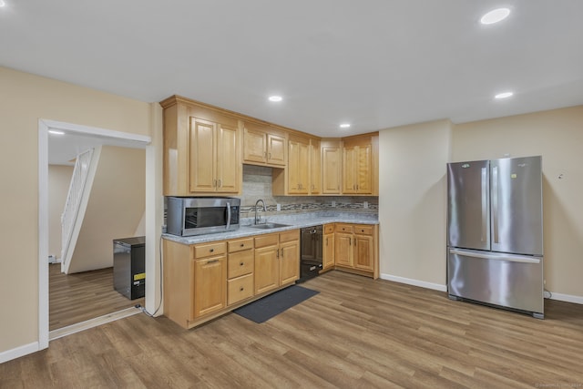 kitchen with stainless steel appliances, sink, light brown cabinets, backsplash, and light hardwood / wood-style flooring