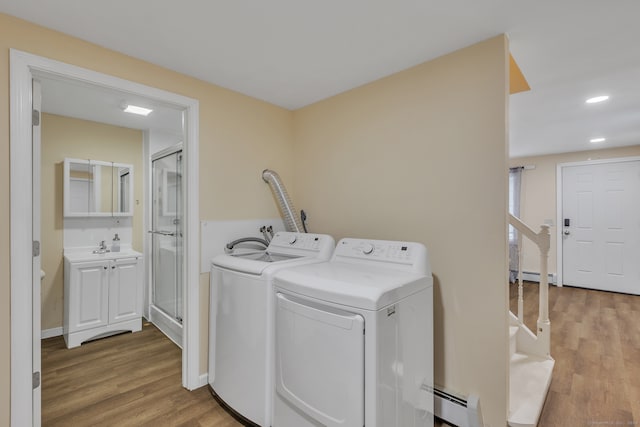 laundry area with washer and clothes dryer, baseboard heating, and light hardwood / wood-style floors