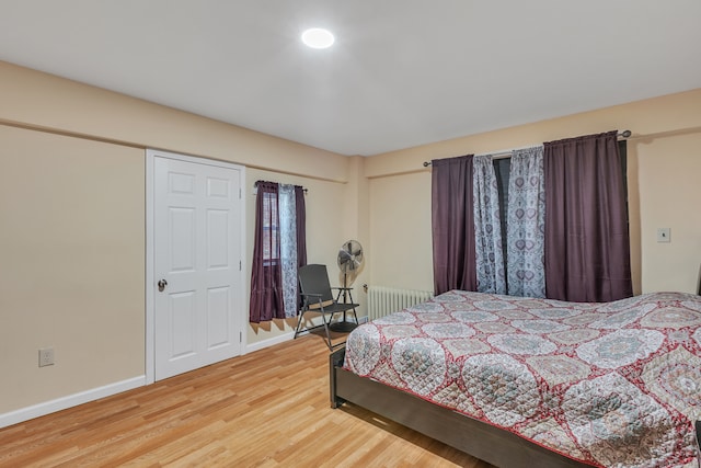 bedroom with radiator heating unit and wood-type flooring