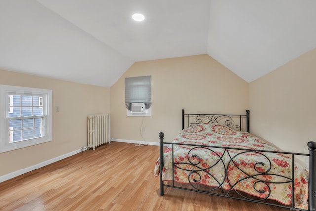 bedroom with hardwood / wood-style flooring, cooling unit, radiator heating unit, and vaulted ceiling