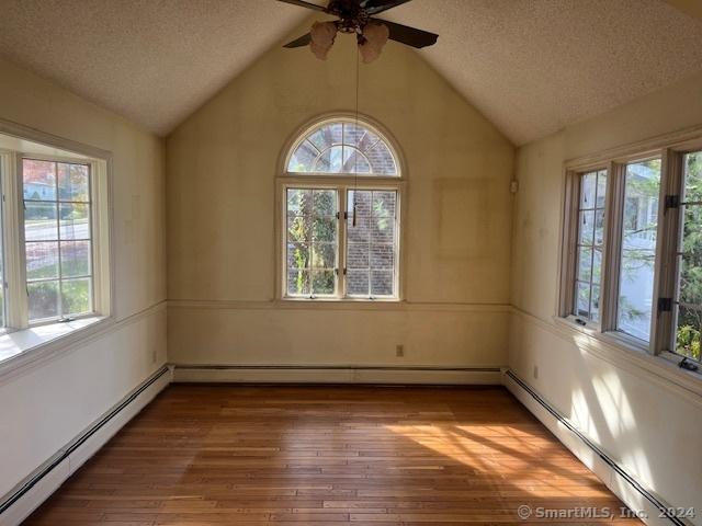 39 Rockefeller Ave, West Haven, CT 06516 - unfurnished room with a baseboard heating unit, a textured ceiling, a ceiling fan, vaulted ceiling, and hardwood / wood-style floors