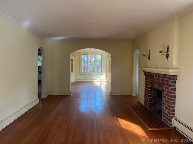 39 Rockefeller Ave, West Haven, CT 06516 - unfurnished living room with a baseboard radiator, arched walkways, wood finished floors, a fireplace, and crown molding