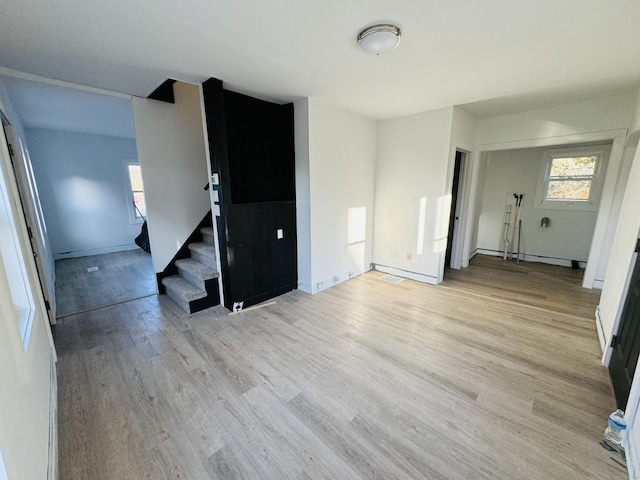 empty room featuring a healthy amount of sunlight, light wood-type flooring, and baseboard heating