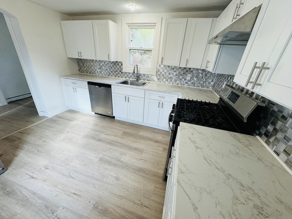 kitchen with sink, stainless steel appliances, light hardwood / wood-style flooring, backsplash, and white cabinets