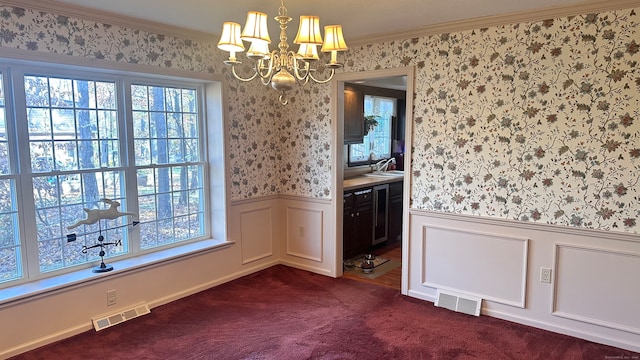 carpeted spare room with sink, crown molding, and an inviting chandelier