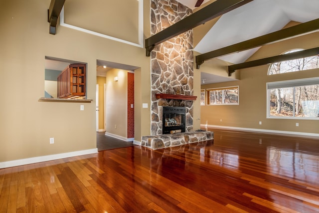 unfurnished living room with high vaulted ceiling, a fireplace, baseboards, and wood finished floors