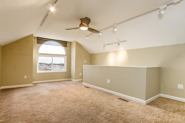 additional living space with visible vents, a ceiling fan, light carpet, vaulted ceiling, and baseboards