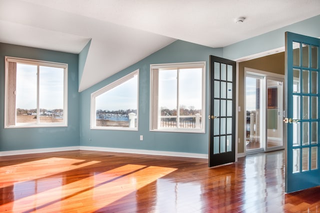 spare room with a textured ceiling, lofted ceiling, french doors, and dark hardwood / wood-style floors