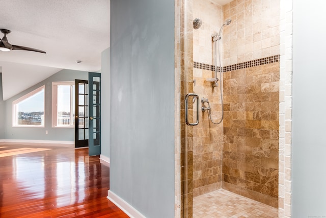 bathroom with a textured ceiling, ceiling fan, wood-type flooring, and a shower with shower door