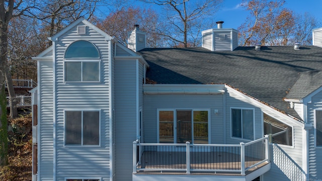 back of property featuring a chimney and roof with shingles