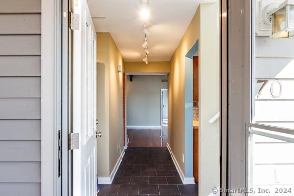 corridor with baseboards and track lighting