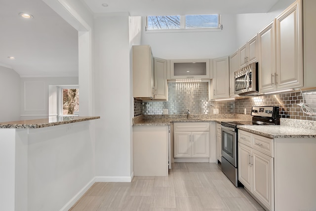 kitchen featuring decorative backsplash, sink, light stone counters, and appliances with stainless steel finishes