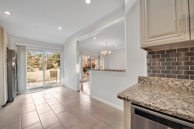 kitchen featuring cream cabinets, stainless steel appliances, backsplash, pendant lighting, and light stone countertops