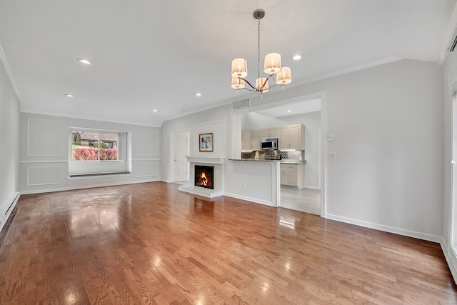 unfurnished living room with a brick fireplace, light hardwood / wood-style floors, an inviting chandelier, and crown molding