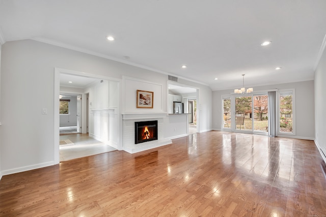 unfurnished living room with ornamental molding, a chandelier, light hardwood / wood-style floors, and a fireplace