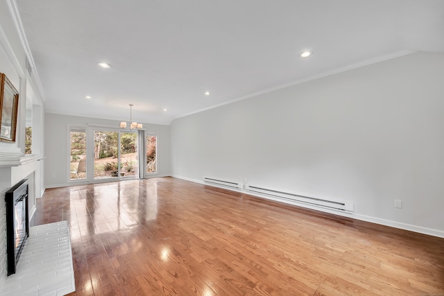 unfurnished living room with light hardwood / wood-style floors, ornamental molding, baseboard heating, a notable chandelier, and a brick fireplace