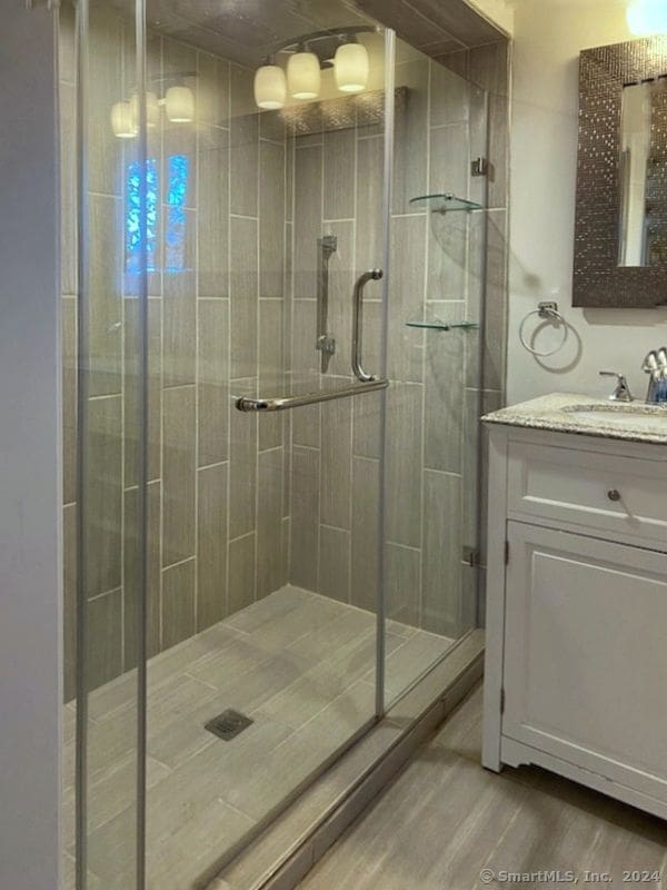 bathroom with vanity, hardwood / wood-style flooring, and a shower with shower door