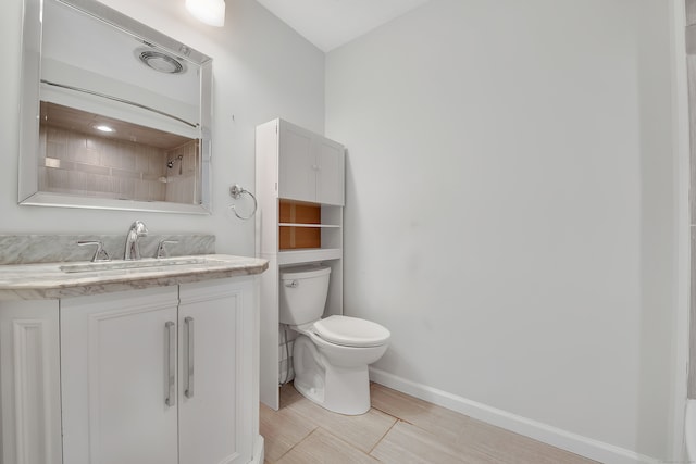 bathroom with tiled shower, vanity, and toilet