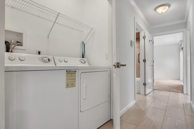 laundry room featuring washing machine and dryer, light colored carpet, a textured ceiling, and crown molding