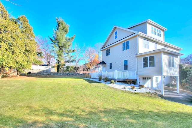 back of property with a garage, a deck, and a yard