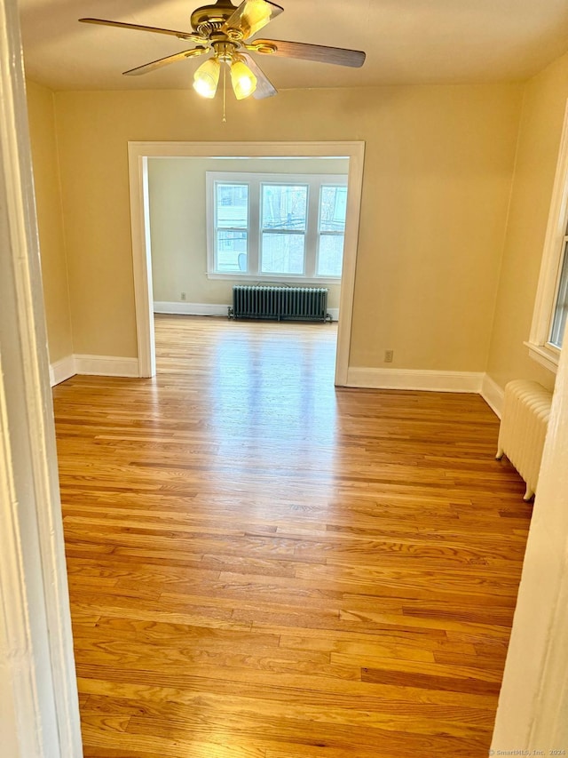 unfurnished room with ceiling fan, radiator heating unit, and light hardwood / wood-style floors