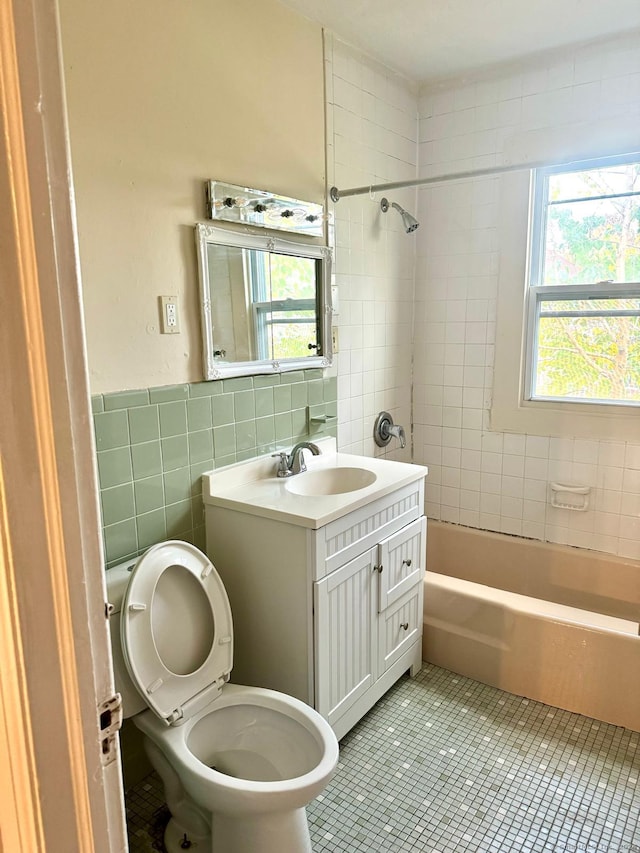 full bathroom with tile patterned floors, toilet, tile walls, tiled shower / bath combo, and vanity