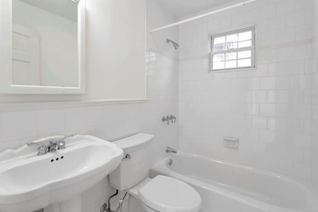 full bathroom with toilet, sink, tile walls, and tiled shower / bath combo